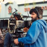 A camera operator filming a street scene for a production
