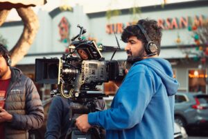 A camera operator filming a street scene for a production